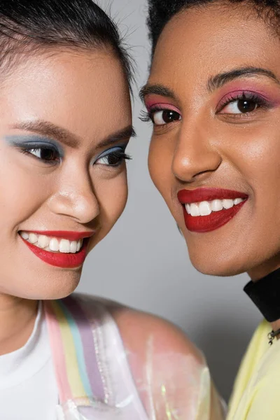Close up view of smiling interracial models with red lips and visage on grey background — Stock Photo