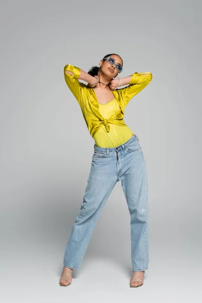 Piena lunghezza di giovane modello afroamericano in abito alla moda e tacchi alti in posa sul grigio — Foto stock