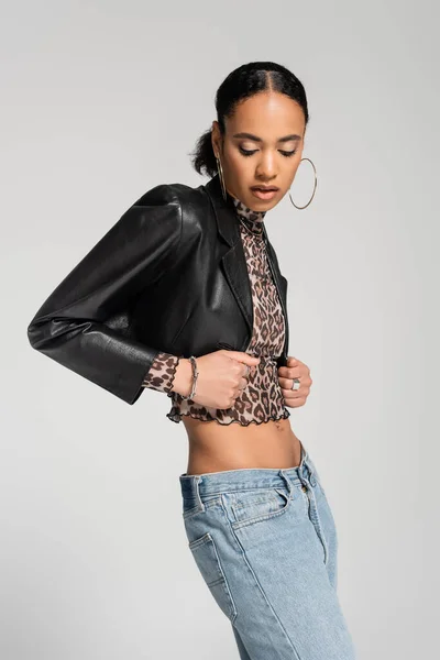 Fashionable african american woman in black cropped jacket posing isolated on grey — Stock Photo
