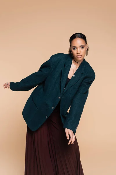 Giovane modella afroamericana in blazer di lana blu scuro e pantaloni larghi in posa isolata su beige — Foto stock