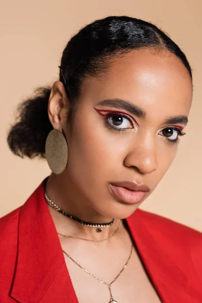Porträt eines stylischen afrikanisch-amerikanischen Modells im roten Blazer, das isoliert in beige in die Kamera blickt — Stockfoto