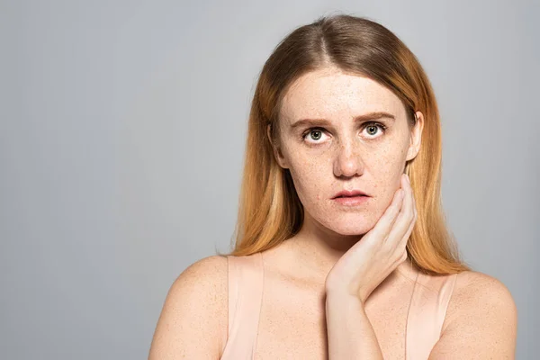 Portrait of freckled model looking at camera isolated on grey — Stock Photo