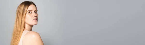Femme avec des taches de rousseur sur la peau regardant la caméra isolée sur gris, bannière — Photo de stock