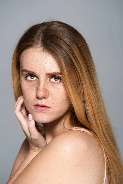 Портрет веснушчатой модели с кожей, смотрящей на камеру, изолированную на сером — стоковое фото