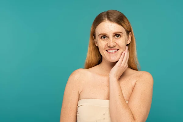 Smiling woman with freckles and naked shoulders posing isolated on turquoise — Stock Photo
