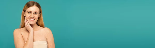 Jeune femme positive avec des taches de rousseur debout isolé sur turquoise, bannière — Photo de stock