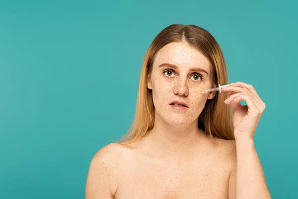 Mulher com problema de pele aplicando soro na bochecha isolada em turquesa — Fotografia de Stock