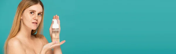 Jeune rousse femme aux taches de rousseur tenant bouteille avec nettoyant mousse isolé sur turquoise, bannière — Photo de stock