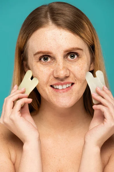 Glückliche Frau mit Sommersprossen mit Jade-Gesichtsschaber isoliert auf Türkis — Stockfoto