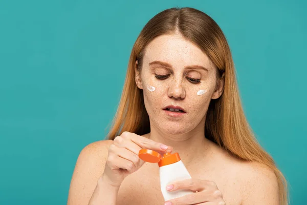 Rothaarige Frau mit Sommersprossen Halteschlauch mit kosmetischer Creme isoliert auf Türkis — Stockfoto