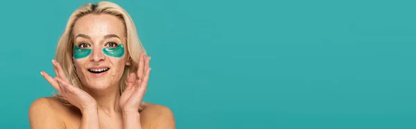 Femme étonnée avec l'acné et les patchs oculaires hydratants souriant isolé sur turquoise, bannière — Photo de stock