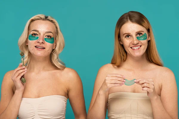 Cheerful women with different skin conditions and patches under eyes smiling isolated on turquoise — Stock Photo