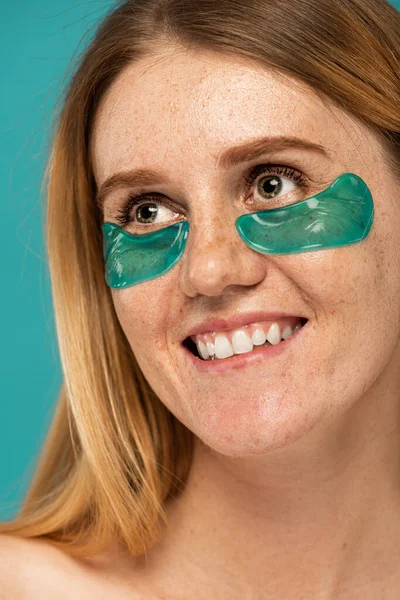 Portrait de femme heureuse avec taches de rousseur et taches de collagène sous les yeux souriant isolé sur turquoise — Photo de stock