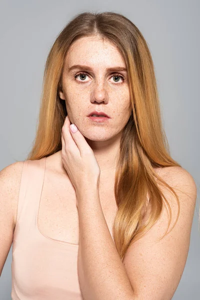 Porträt einer sommersprossigen jungen Frau mit roten Haaren, die isoliert auf grau in die Kamera blickt — Stockfoto