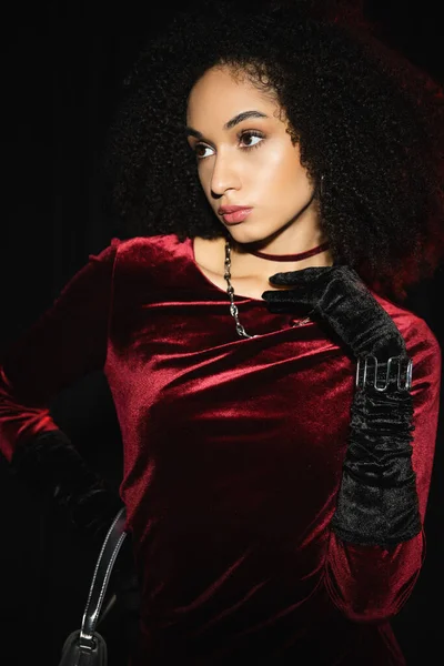 Stylish african american woman in velvet dress and glove isolated on black — Stock Photo