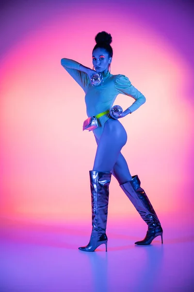 Volle Länge der trendigen afrikanisch-amerikanischen Modell mit Neon-Visage hält Discokugeln auf rosa und lila Hintergrund — Stockfoto