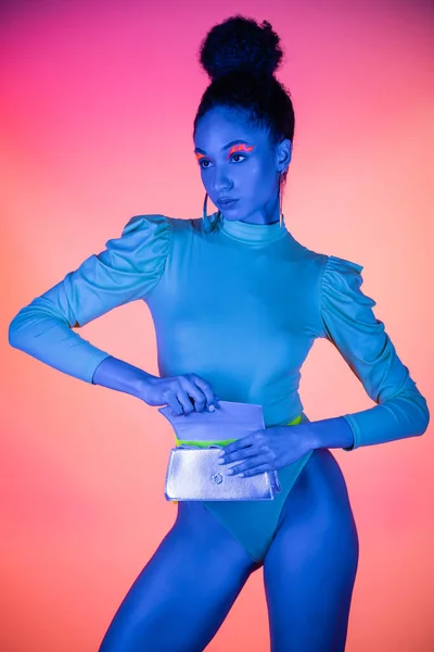 Hübsches afrikanisch-amerikanisches Modell mit Neon-Visage und Body-Opening-Taille auf hellrosa Hintergrund — Stockfoto