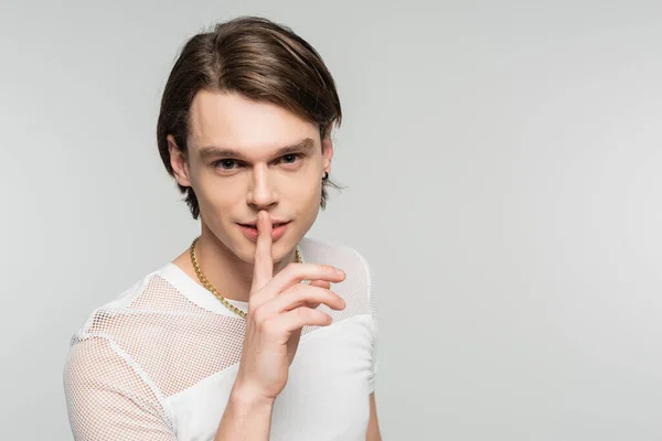 Junges Pangender-Model in weißem T-Shirt blickt in die Kamera und zeigt Schweigezeichen isoliert auf grau — Stockfoto