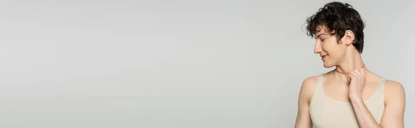 Profilo di giovane bigender modello in canotta toccante perline colorate e sorridente isolato su grigio, banner — Foto stock