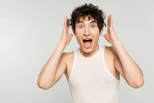 Sorprendido pansexual persona con la boca abierta mostrando wow gesto y mirando cámara aislada en gris - foto de stock