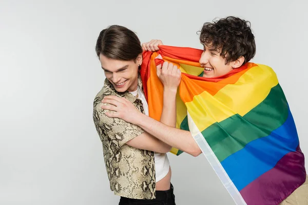 Alegres socios más grandes con la bandera del arco iris divertirse aislado en gris - foto de stock
