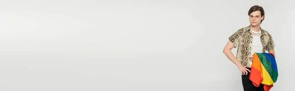 Pessoa maior na blusa de impressão de pele de cobra de pé com a mão no quadril e segurando bandeira lgbt isolado em cinza, banner — Fotografia de Stock