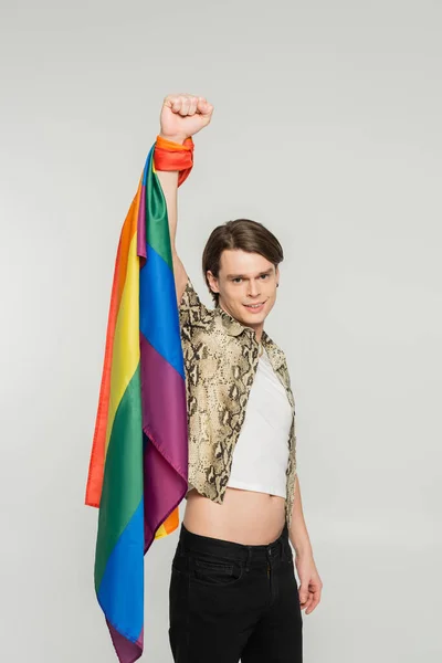 Счастливый бисексуал с флагом США, показывающий выигрышный жест и улыбающийся камере на сером фоне — стоковое фото