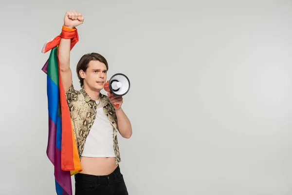 Trendy bigender person with lgbt flag shouting in loudspeaker isolated on grey — Stock Photo