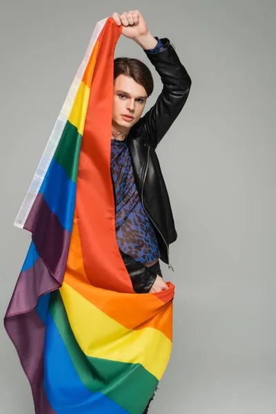 Modelo pansexual joven y de moda posando con bandera lgbt aislada en gris - foto de stock