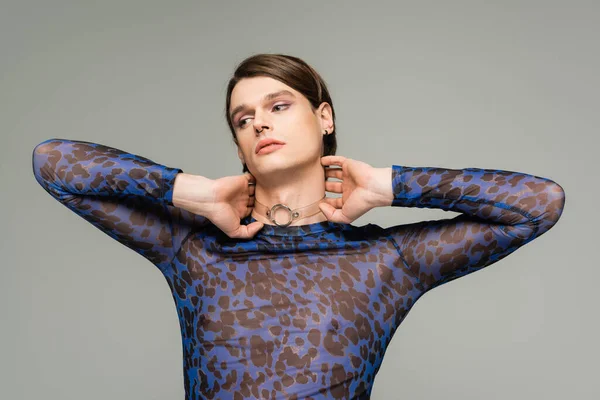 Fashionable pansexual person in blue animal print top touching neck and looking away isolated on grey — Stock Photo