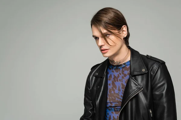 Trendy and confident bigender person in black leather jacket looking away isolated on grey — Stock Photo