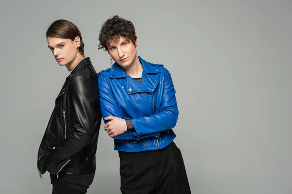 Junges pansexuelles Paar in Lederjacken blickt isoliert in die Kamera auf grau — Stockfoto