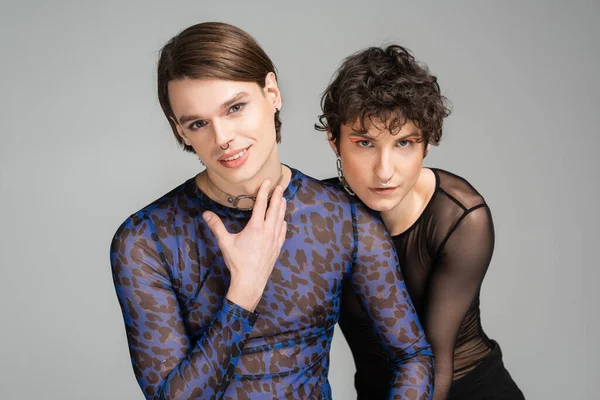 Trendy bigender Paar mit Make-up Blick auf Kamera isoliert auf grau — Stockfoto