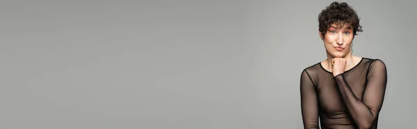 Modèle pansexuel gai en haut transparent noir regardant la caméra isolée sur gris, bannière — Photo de stock
