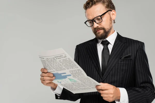 Businessman in suit and glasses reading newspaper isolated on grey — Stock Photo