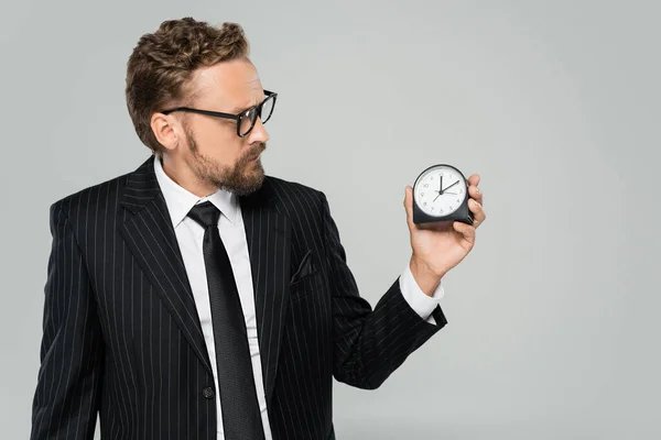 Businessman in glasses and formal wear holding vintage alarm clock isolated on grey — Stock Photo