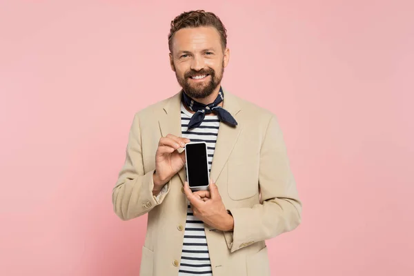 Glücklich französischer Mann in Blazer und Halstuch hält Smartphone mit leerem Bildschirm isoliert auf rosa — Stockfoto
