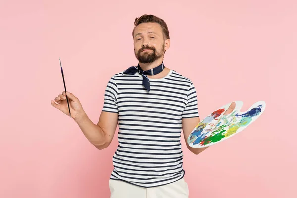 Barbu artiste français avec écharpe cou tenant palette avec peintures colorées et pinceau isolé sur rose — Photo de stock
