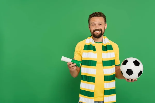 Feliz fanático del fútbol celebración de deportes cuerno y fútbol aislado en verde - foto de stock