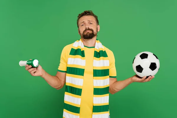 Бородатый футбольный болельщик держа спортивный рог и футбол изолированы на зеленый — стоковое фото