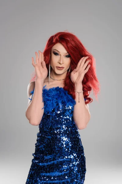 Pelirroja drag queen en vestido azul mirando a la cámara aislada en gris - foto de stock
