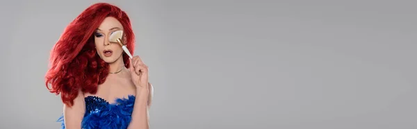 Élégante drag queen tenant un pinceau cosmétique près du visage isolé sur gris, bannière — Photo de stock