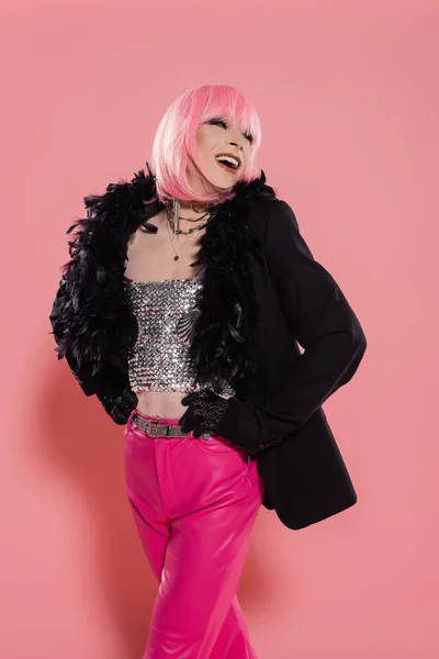 Carefree transgender person in jacket with feathers posing on pink background — Stock Photo