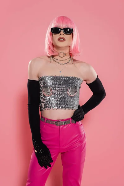 Fashionable drag queen in sunglasses and sparkling top posing on pink background — Stock Photo