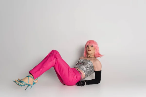 Fashionable drag queen in top and heels lying on grey background — Stock Photo