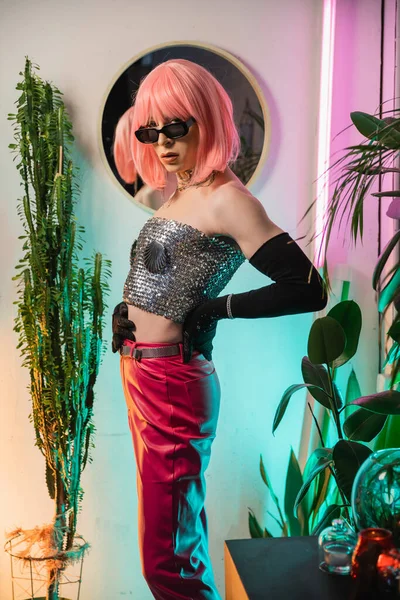 Trendige Transgender-Person mit Sonnenbrille und glänzendem Oberteil schaut zu Hause in die Kamera — Stockfoto