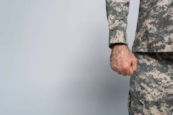 Vista cortada de soldado patriótico em uniforme militar de pé com punho cerrado em fundo cinza — Fotografia de Stock