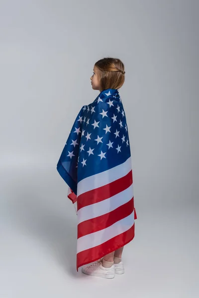 Patriotic preteen girl wrapped in flag of America during memorial day on grey — Stock Photo