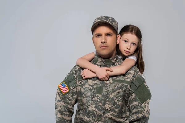 Preteen menina abraçando bravo pai no exército uniforme durante memorial dia isolado no cinza — Fotografia de Stock