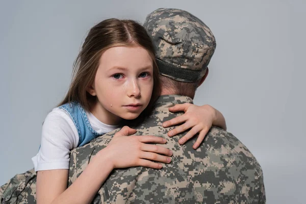 Patriotic girl hugging father in army uniform and crying during memorial day isolated on grey — Stock Photo